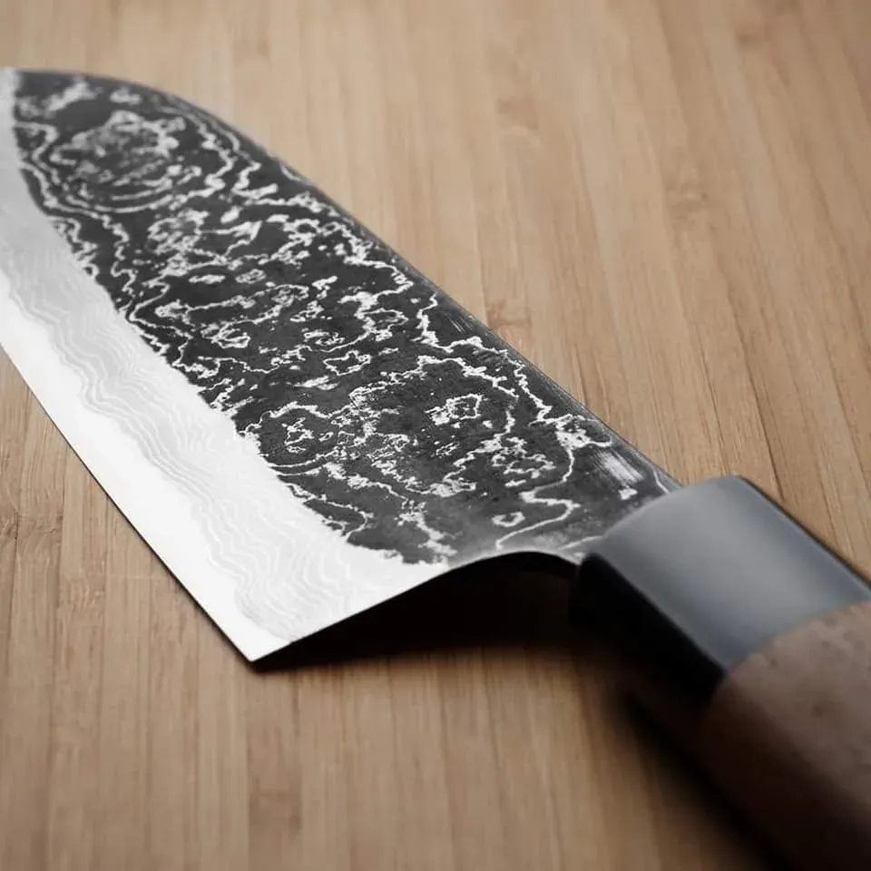 Gros plan sur le fil d’une lame de couteau finement affûtée, posée sur une planche de bois.